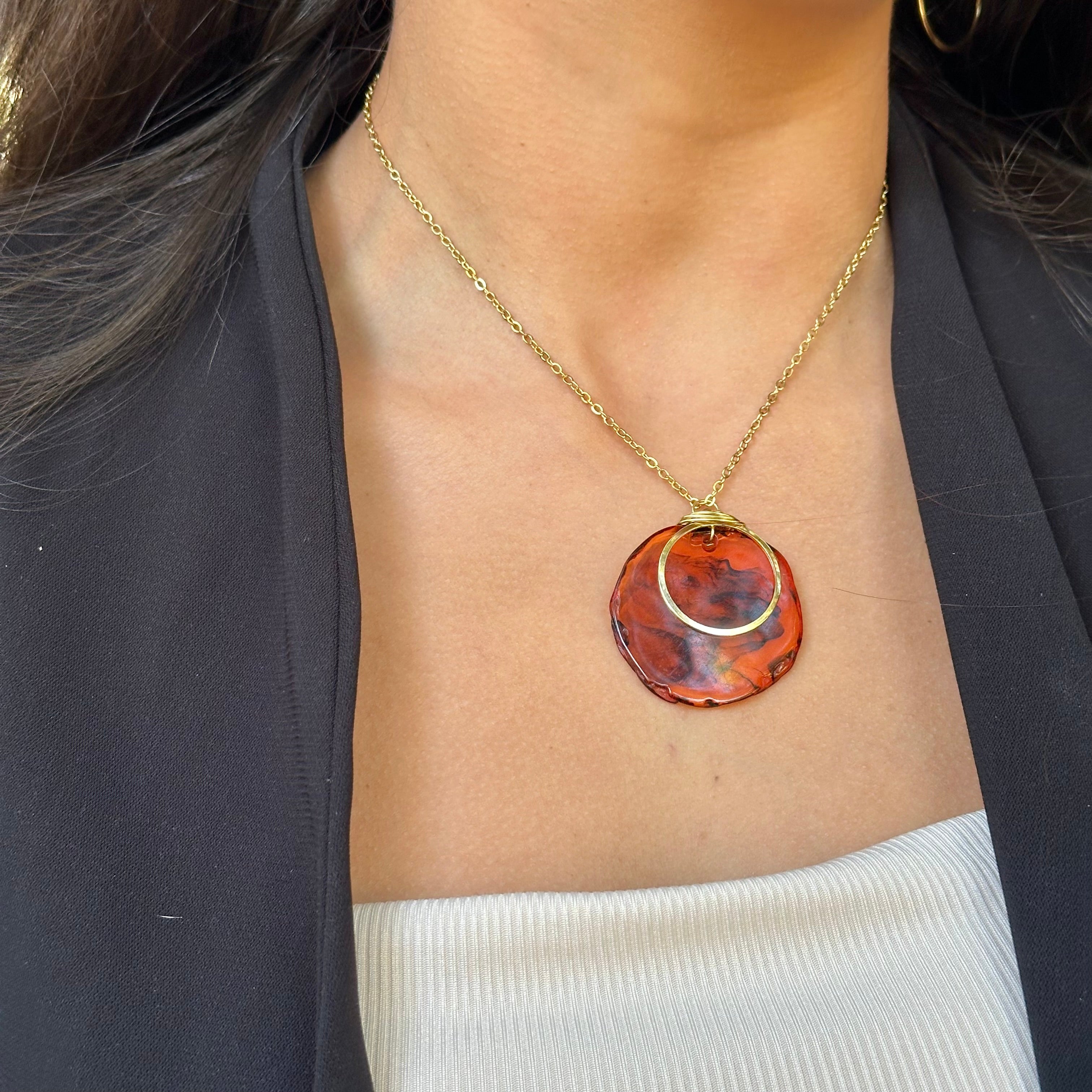 Necklace with a red and gold pendant worn by a person