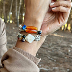 Hand wearing multiple bracelets with a natural background