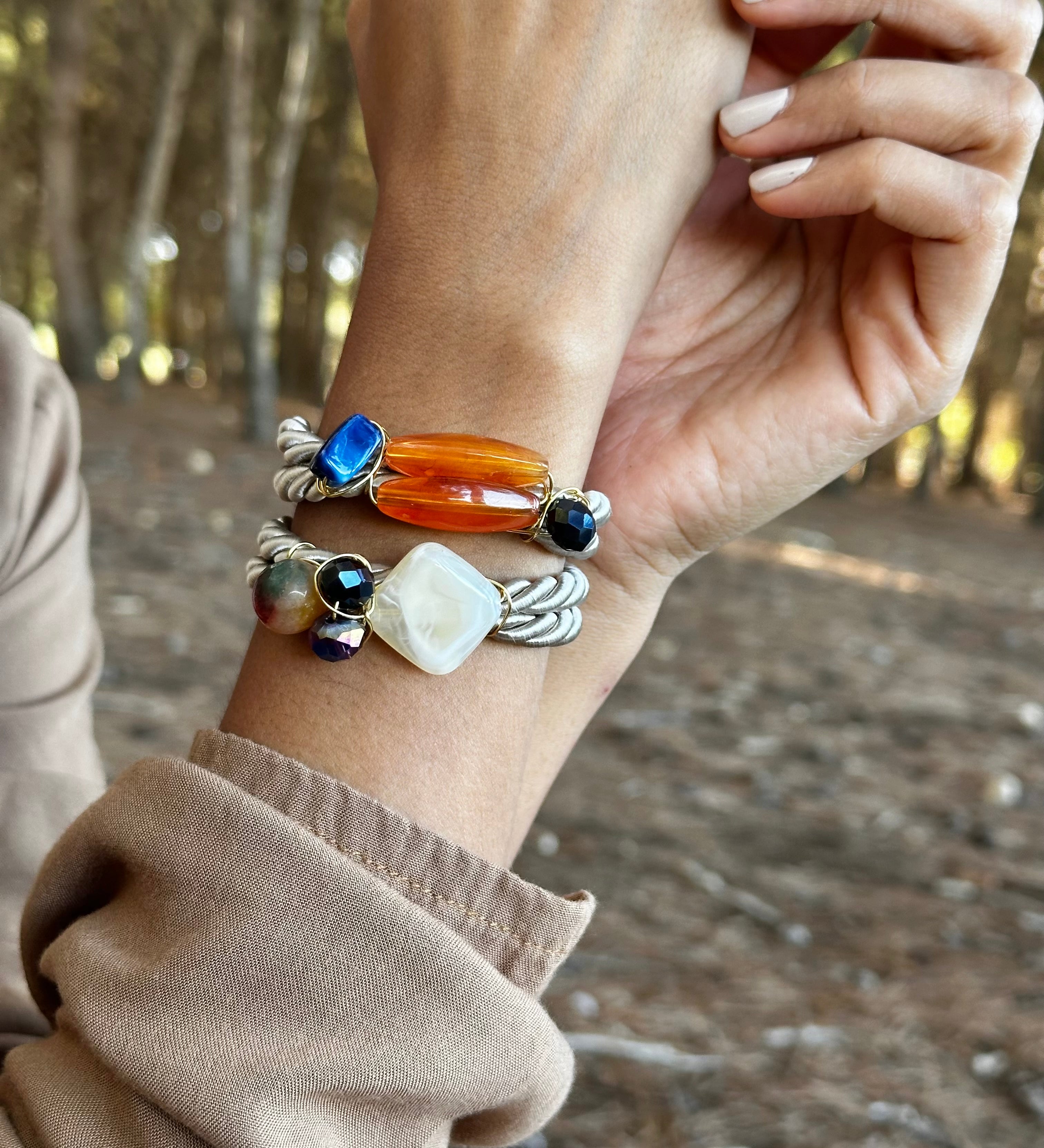Hand wearing multiple bracelets with a natural background