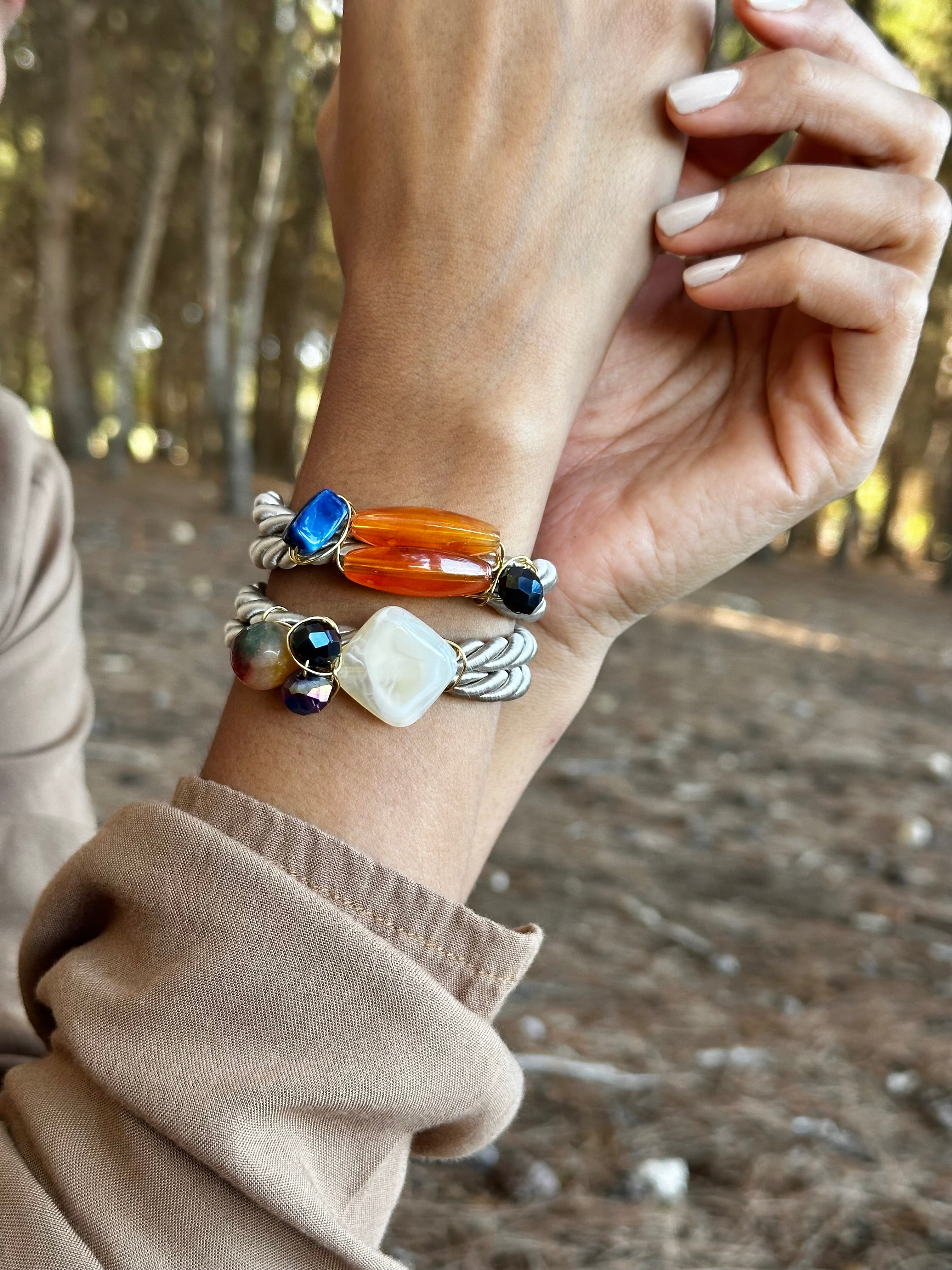 Hand wearing multiple bracelets with a natural background