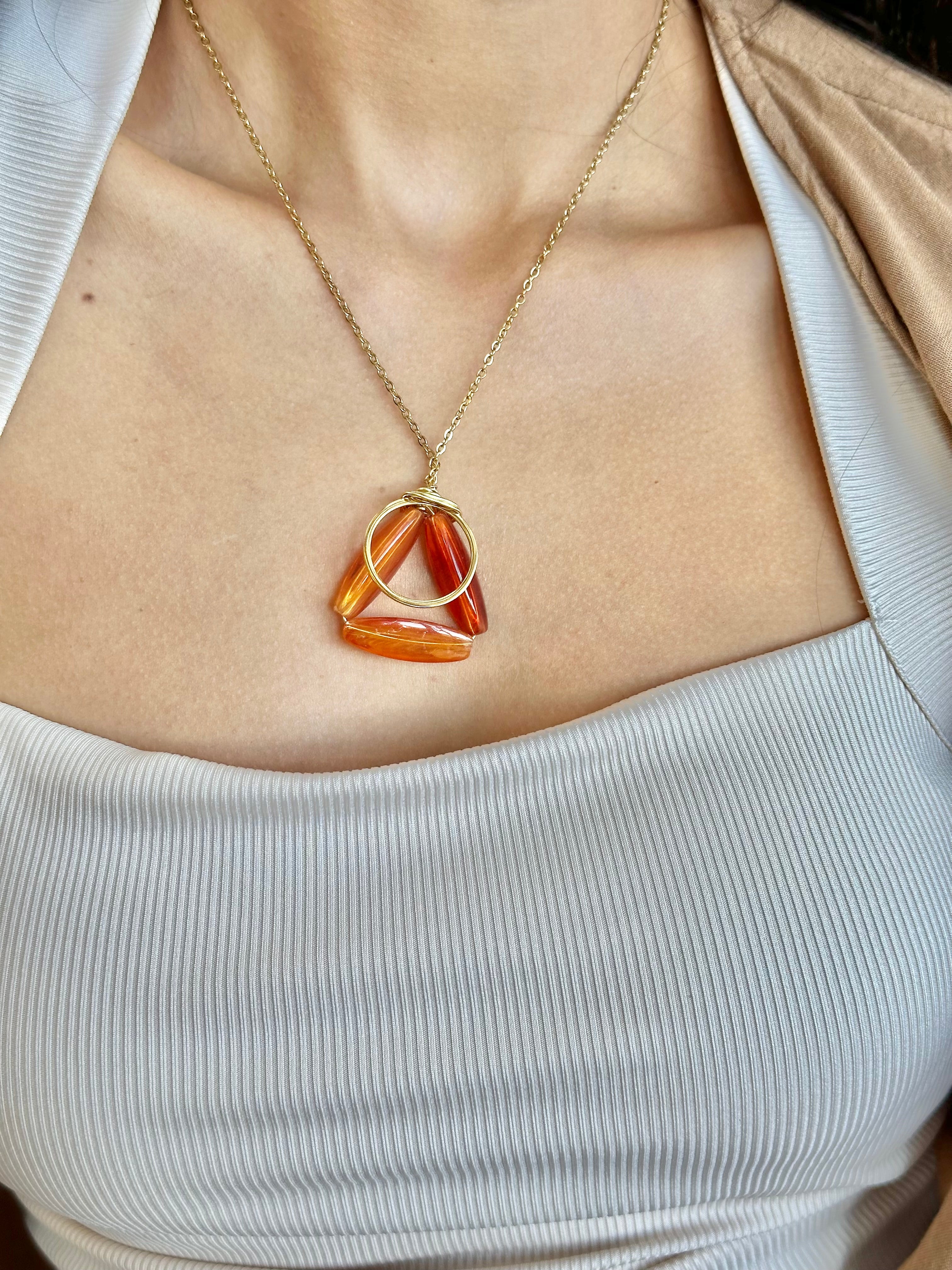 Necklace with a triangular pendant worn by a person